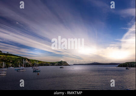 Dramatischer Sonnenuntergang vom Waiheke nach Auckland inter gesehen - Island Fähre. Ruhige Bucht mit Segeln Boote vor Anker, gegen die Wolken mit Hintergrundbeleuchtung Stockfoto