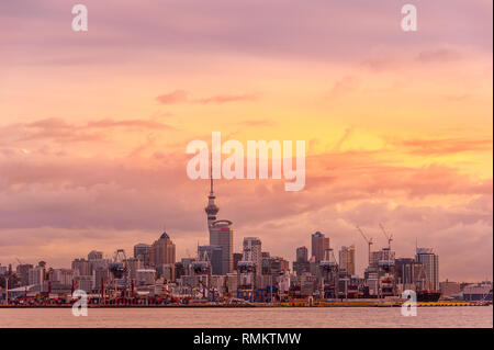 Auckland, Neuseeland - Juli, 2018: Die Skyline der Stadt mit Skytower, Container Terminal und bunten Sonnenuntergang Himmel Hintergrund Stockfoto