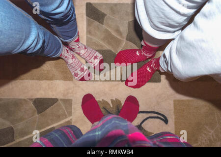 Lustige Bild von Freunden Beine in Rot Urlaub Socken auf dem Teppich Stockfoto