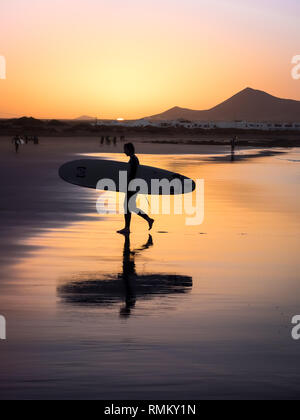 Silhouette einer Surfer am Famara Strand bei Sonnenuntergang, Kanarische Insel Stockfoto