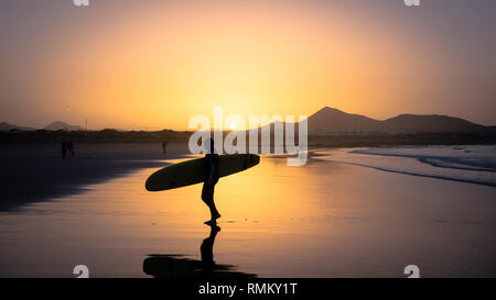 Silhouette einer Surfer am Famara Strand bei Sonnenuntergang, Kanarische Insel Stockfoto