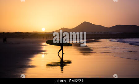 Silhouette einer Surfer am Famara Strand bei Sonnenuntergang, Kanarische Insel Stockfoto