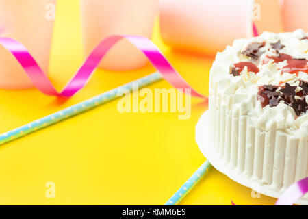 Schwamm layer Geburtstag Kuchen mit Sahne frosting Schokolade star besprüht strawberry jam. Rosa Papier Trinkbecher blau Trinkhalme curly Band auf y Stockfoto