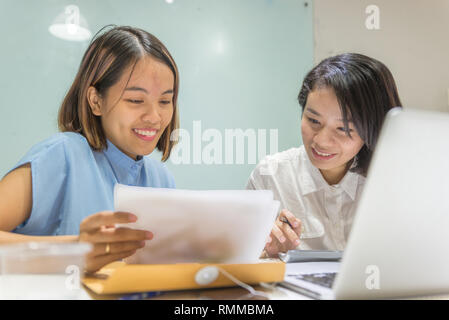 Junge asiatische Büro Frau mit Partner über Dokument diskutieren Stockfoto