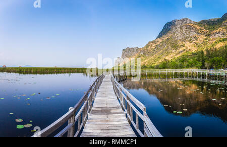 Die schöne Landschaft der hölzernen Brücke Gehweg im Sumpf mit Rasenfläche mit blauem Himmel Gebirge Hintergrund in Khao Sam Roi Yot Nationalpark, Kui Stockfoto