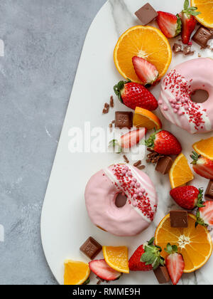 Eine gemischte Obstplatte mit Donuts auf einem dunklen Hintergrund Stockfoto