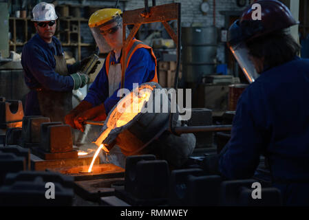 Gießer geschmolzenes Eisen in Formen für die Herstellung von Gitterrosten Feuer gießen Stockfoto