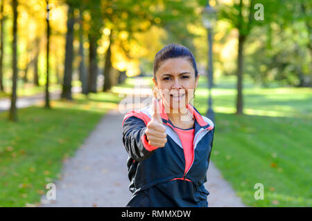 Portrait von erwachsenen Frau tragen Sportswear Daumen hoch geben im Park Stockfoto