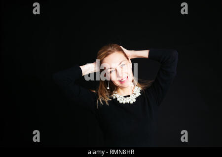 In der Nähe von Studio Portrait einer schönen Frau im schwarzen Kleid auf schwarzem Hintergrund Stockfoto