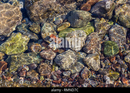 Bunte Steine unter Wasser im Meer mit Reflexionen der Sonne Stockfoto