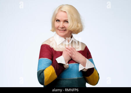 Schöne ältere Frau mit farbigen Pullover ist mit Kompliment berührt Stockfoto