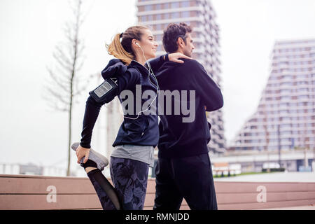 Männliche Trainer helfen jungen Frau Training im Freien in städtische Umwelt Stockfoto