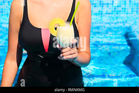 Frau mit Glas pinacolada Cocktail in der Hand am Pool in einem tropischen Resort Stockfoto