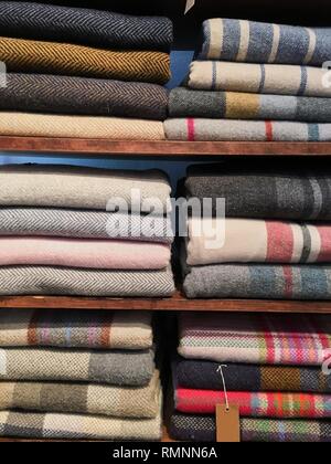 Blumenstrauß aus warmen gestrickten Pastellfarben der verschiedenen Stoffdessins in einem Stapel auf Weiß. Herbst Winter saison modische Strickwaren. Stockfoto