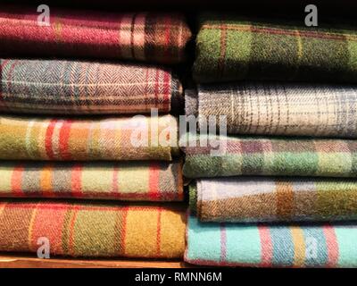 Blumenstrauß aus warmen gestrickten Pastellfarben der verschiedenen Stoffdessins in einem Stapel auf Weiß. Herbst Winter saison modische Strickwaren. Stockfoto