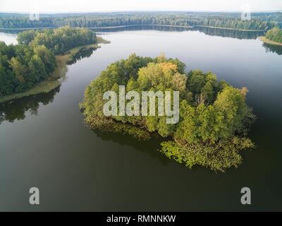 Luftaufnahme der kleine unbewohnte Insel (Wyspa Pozeracza Serc) auf See mit Sky in ruhigem Wasser im Herbst Jahreszeit wider, krzywa Kuta See, Masuren Stockfoto