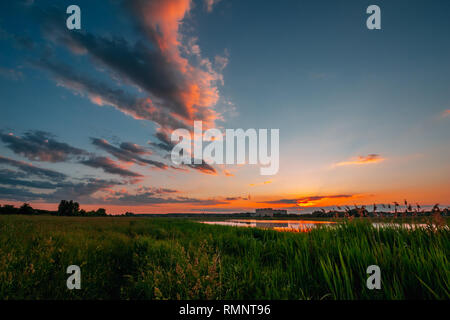 Landschaft mit Feld- und See widerspiegeln Orange am Horizont nach Sonnenuntergang Stockfoto