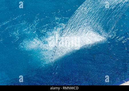 Leere blue water Pool mit Wasserfall stream in Aktion. Entspannung Pool, Spa Hydrotherapie. Das Konzept der Hydromassage und Entspannung. Stockfoto