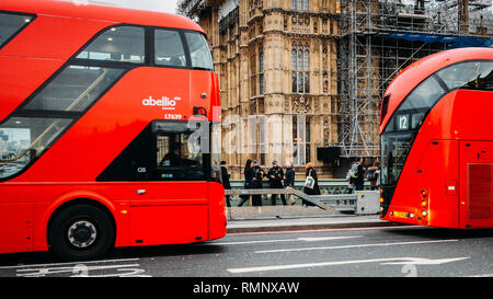 London - Feb 12, 2019: Bewaffnet bis an die Zähne zwei Polizisten sorgen für Sicherheit auf die Westminster Bridge, London von zwei roten Busse Decker gerahmt Stockfoto