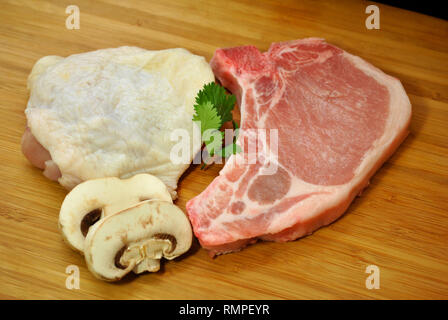 Rohes Huhn Oberschenkel, Porkchop, & Pilze Stockfoto