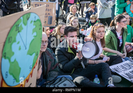 Eine Gruppe der Teilnehmer hören sie die Rede von ein Demonstrant während das Klima Streik in London gemacht. Tausende von der Grundschule, Kinder, Jugendliche und Studenten haben heute aus Unterricht in mehr als 40 Städten und Gemeinden des Vereinigten Königreichs gegen den Klimawandel zu protestieren und die Regierung zum Handeln drängen. Die globale Bewegung wurde von Teenager Aktivistin Greta Thunberg, die Schule schwänzen wurde jeden Freitag seit August außerhalb des schwedischen Parlaments zu protestieren inspiriert worden. Stockfoto