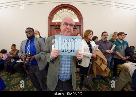 Mineola, New York, USA. 15 Feb, 2019. ERIC WELTMAN, Brooklyn, ein älterer Veranstalter für Food & Water Watch in New York, hält ein Blue Card mit 100 % 2030 auf, die sich auf Ziel von 100% saubere Energie bis 2030, während der nys Senat Öffentliche Anhörung über Klimawandel, Community and Protection Act, Bill S 7253, Sen. Kaminsky, Vorsitzender des Senats Ständigen Ausschusses für Umweltschutz gefördert. Diese 3. Öffentliche Anhörung zum Gesetzesentwurf zur Bekämpfung des Klimawandels wurde auf Long Island. Long Island. Quelle: Ann Parry/ZUMA Draht/Alamy leben Nachrichten Stockfoto