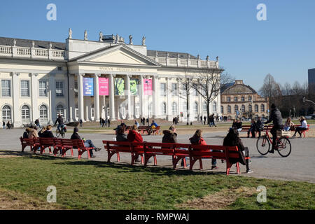 Kassel, Deutschland. 16 Feb, 2019. Zahlreiche Leute sitzen auf rote Bänke auf den Friedrichsplatz vor dem Fridericianum bei sonnigem Wetter. Quelle: Uwe Zucchi/dpa/Alamy leben Nachrichten Stockfoto