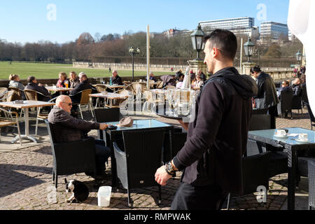 Kassel, Deutschland. 16 Feb, 2019. Eine Kellnerin geht mit einem vollen Tablett zu den ersten Gästen, die im Cafe vor der Orangerie niedergelassen haben. Quelle: Uwe Zucchi/dpa/Alamy leben Nachrichten Stockfoto