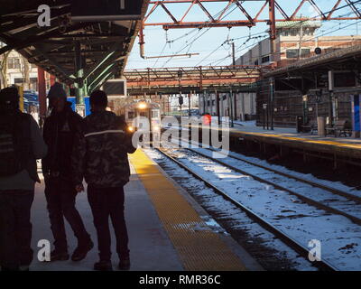 Drei Afrikanisch-amerikanische Männer warten auf einen New Jersey Transit Zug Richtung Westen auf dem Gipfel, New Jersey Station auf einem verschneiten Nachmittag. Stockfoto