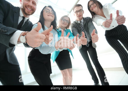 Ansicht von unten. Business Team in die Kamera schaut und zeigen ihre Daumen nach oben. Stockfoto
