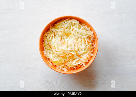 Orange Schale Zerkleinert Gemüse mit rohen gehackten Kohl und Möhren, gesehen von oben auf weißem Hintergrund Oberfläche Stockfoto