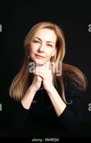 In der Nähe von Studio Portrait einer schönen Frau im schwarzen Kleid auf schwarzem Hintergrund Stockfoto