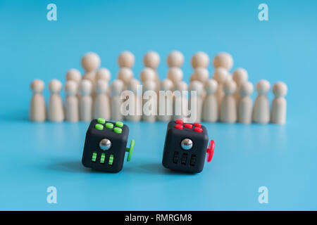 Menge Ruhe Konzept. Antwort wie die Menge zu beruhigen. Fidget Cube Druckhelfer und Holzfiguren auf einem blauen Hintergrund. Stockfoto