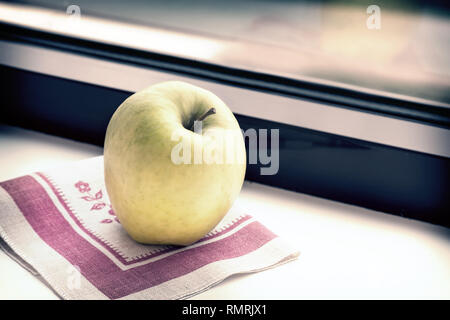 Auf dem Fensterbrett auf eine Serviette reif gelb Apple. Stockfoto