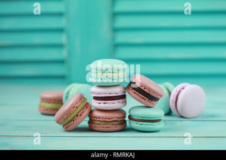 Macaron oder Makronen auf Türkisfarbenem Hintergrund, bunte almond Cookies mit unterschiedlicher Füllung. Selektiver Fokus Stockfoto