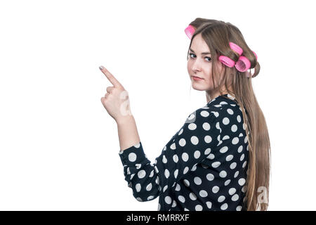 Schöne Frau in Lockenstäbe steht mit dem Rücken zur Kamera gedreht, Punkten seitwärts und nach oben, auf weißem Hintergrund Stockfoto