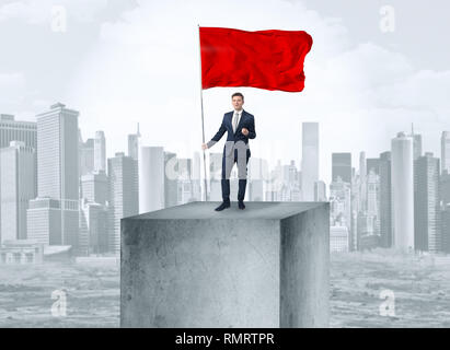 Gut aussehender Geschäftsmann auf der Oberseite der Stadt mit Red Flag Stockfoto