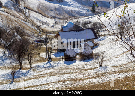 Zwei Heuballen mit Schnee bedeckt, in der Nähe einer isolierten, ländlichen Haus, in einem Tal in Magura Village, Rumänien, an einem sonnigen Morgen, kurz nach dem ersten Schnee Stockfoto