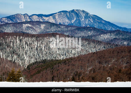 Schichten der Bergrücken in den Karpaten, Rumänien, während einer Winterwanderung. Postavaru Massiv im Hintergrund. Stockfoto