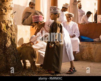 Nizwa, Oman - November 2, 2018: Omani Kinder spielen mit Tieren zum nizwa Freitag Markt Stockfoto