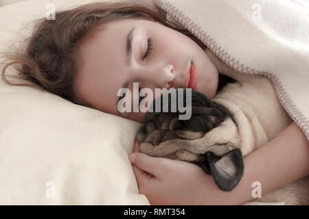 Recht jugendlich Mädchen schlafen Umarmen einen Mops Hund im Bett Stockfoto