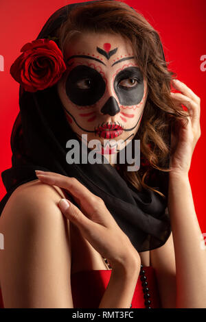 Junge Frau mit Santa muerte Make-up auf rotem Hintergrund Stockfoto