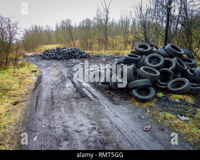 Stapel von alten Reifen am Ende einer Landstraße entleert. Sind sie Fliegen- oder Links für die Wiederverwendung durch Landwirt? Stockfoto