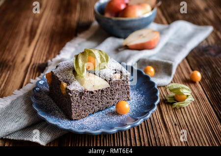 Mohn Kuchen mit Physalis und Birne, bestreut mit Puderzucker Stockfoto