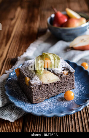 Mohn Kuchen mit Physalis und Birne, bestreut mit Puderzucker Stockfoto