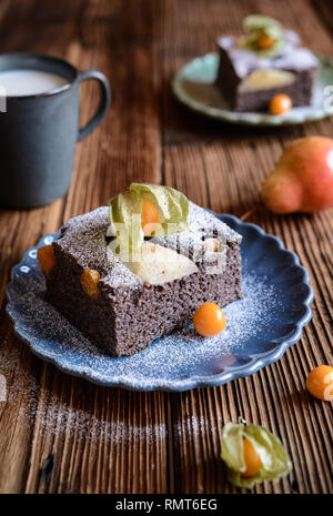 Mohn Kuchen mit Physalis und Birne, bestreut mit Puderzucker Stockfoto