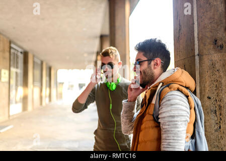 Zwei junge Männer sprechen über das Telefon in der City passage Stockfoto