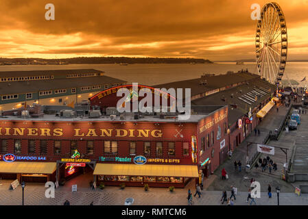 Die Seattle Downtown waterfront in der Dämmerung mit dem Riesenrad und Shops auf den Piers. Stockfoto