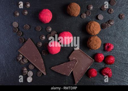 Thema süße Nachspeise Kuchen handgefertigt. Makro close-up Dessert süße Candy runde Kugel Trüffel Satz schwarze Schokolade Kakao Himbeere puer auf einem schwarzen backgr Stockfoto