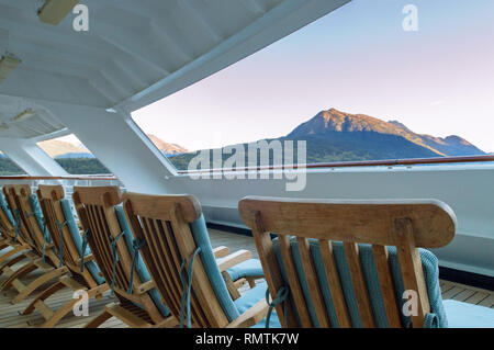 Reihe offener gepolsterten bewaldeten Deck Lounge Sessel bei Sonnenaufgang am frühen Morgen auf der Veranda am Heck des Kreuzfahrtschiff, Skagway, Alaska, USA. Stockfoto